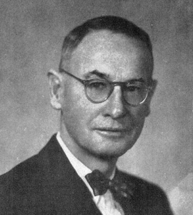 Black and white photo of man in glasses, suit and bowtie