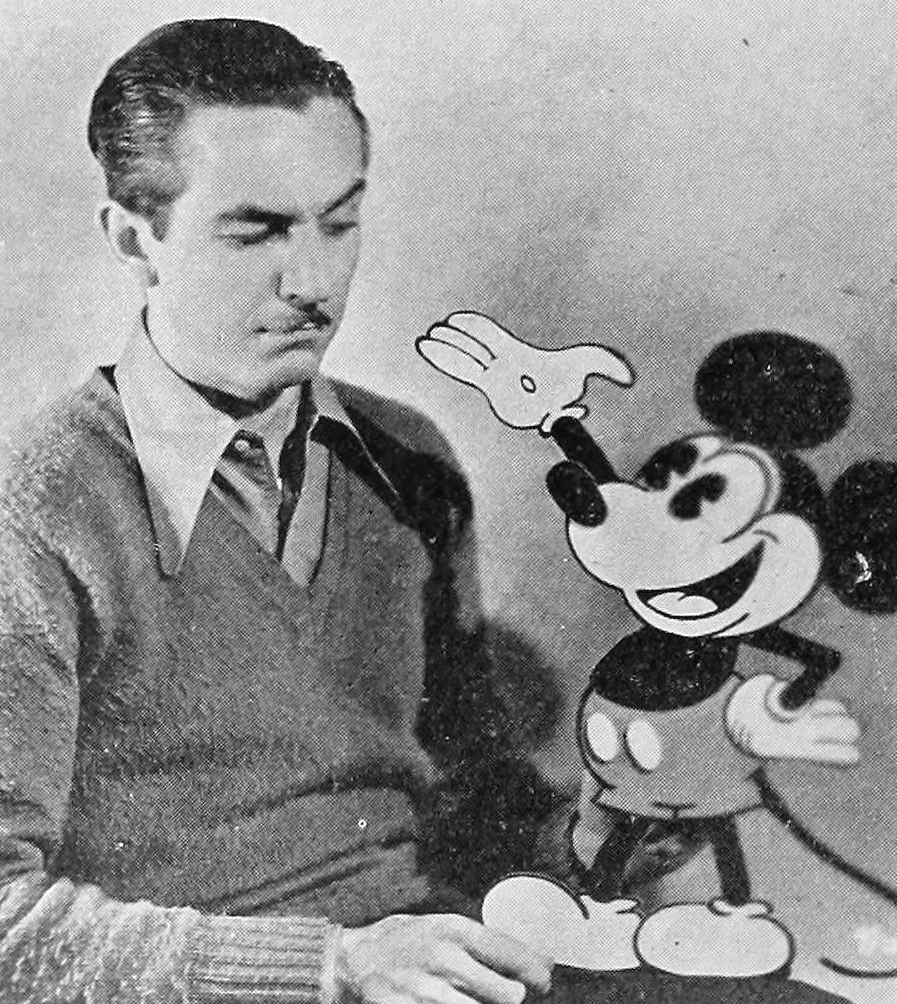 Walt Disney holding a three dimensional cut out of Mickey Mouse